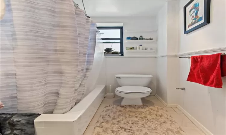 Bathroom with toilet and shower / tub combo with curtain