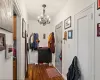 Corridor featuring dark wood-type flooring and a notable chandelier