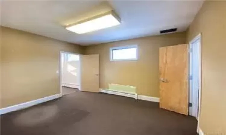 Empty room featuring a baseboard radiator and dark carpet