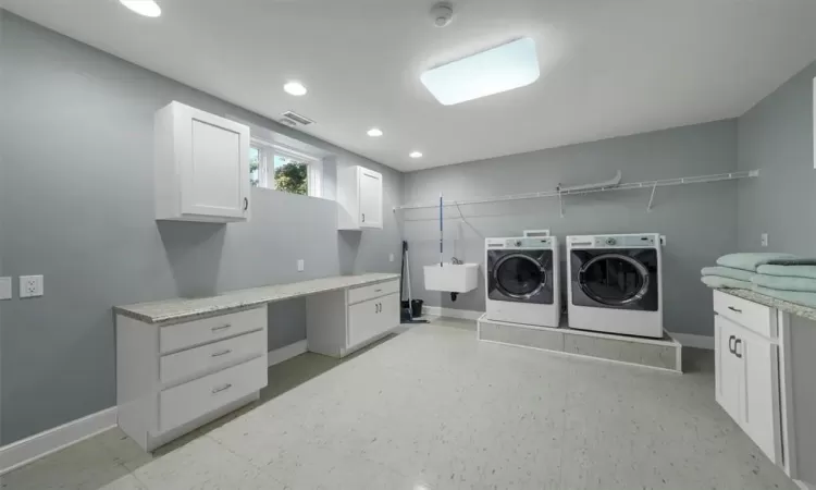 Laundry area featuring sink, washing machine and dryer, cabinets, and light tile patterned floors, has a shoot from upstairs.