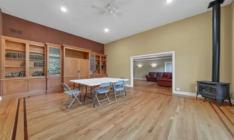 Dining space with ceiling fan, light wood-type flooring, and a wood stove