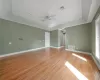 Master bedroom with ceiling fan, a raised ceiling, and light hardwood / wood-style flooring