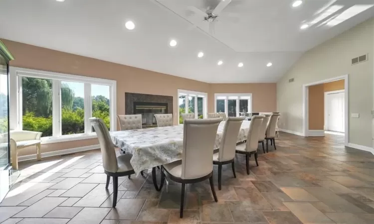 Tiled dining area with a wealth of natural light, lofted ceiling, and ceiling fan