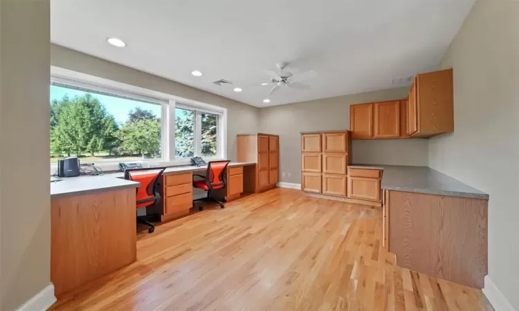 Office featuring ceiling fan, built in desk, and light hardwood / wood-style flooring