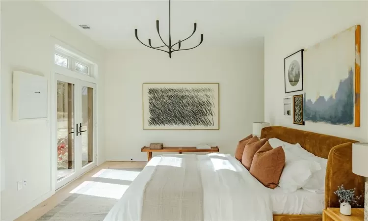 Bedroom with access to outside, a chandelier, french doors, and light hardwood / wood-style flooring