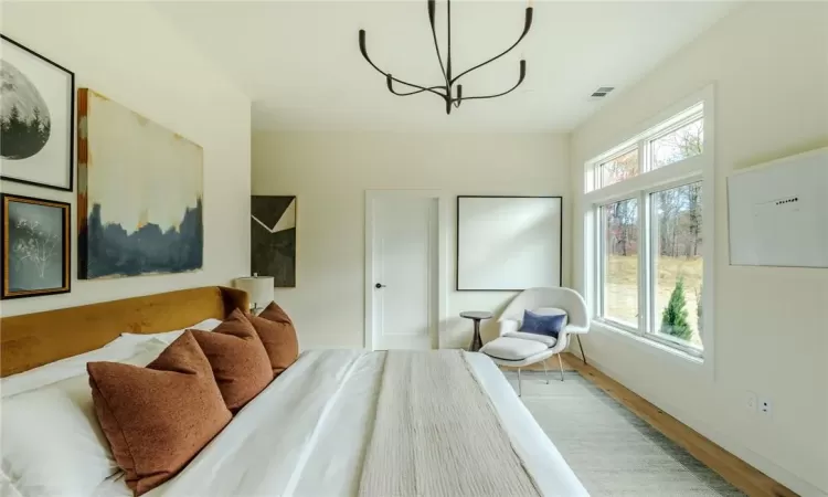 Bedroom with wood-type flooring and an inviting chandelier