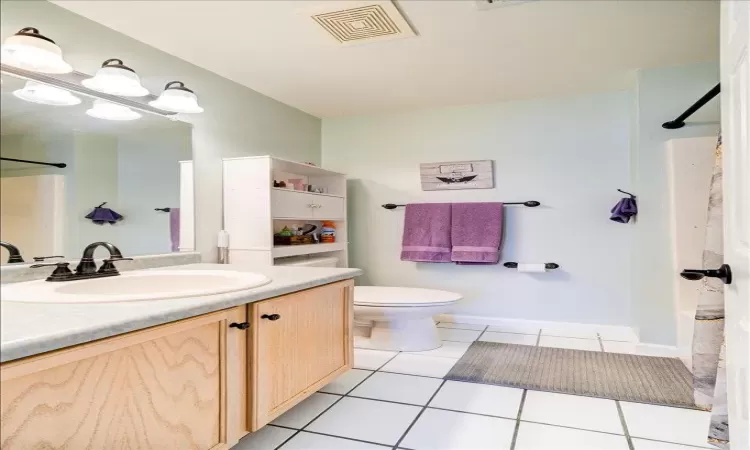 Bathroom with vanity, walk in shower, tile patterned floors, and toilet