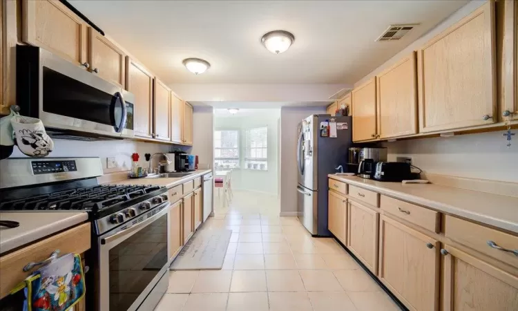 Kitchen featuring appliances with stainless steel finishes, sink, light brown cabinetry, and light tile patterned flooring