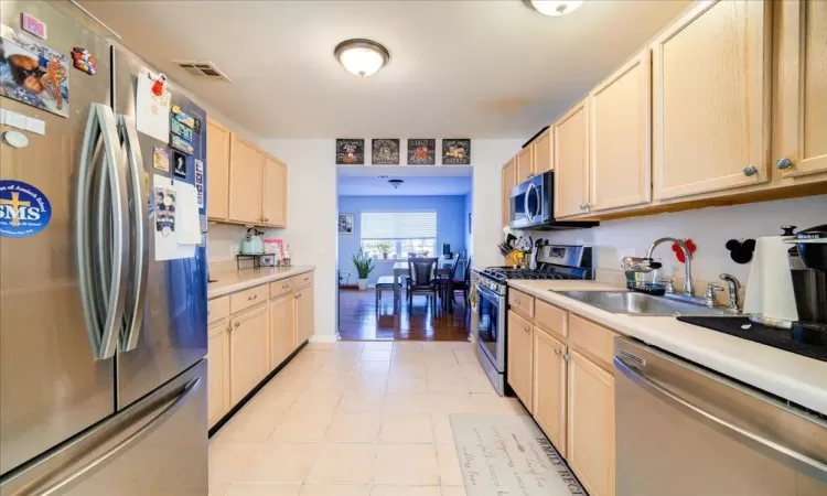 Kitchen with light brown cabinetry, appliances with stainless steel finishes, and sink