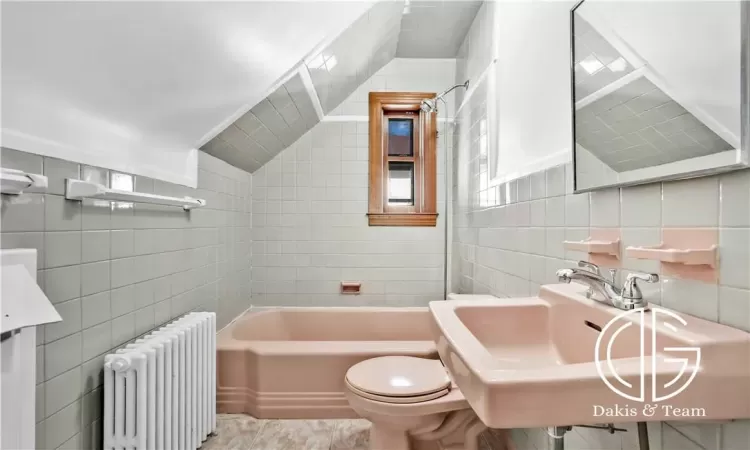 Bathroom featuring tile walls, sink, radiator heating unit, and toilet