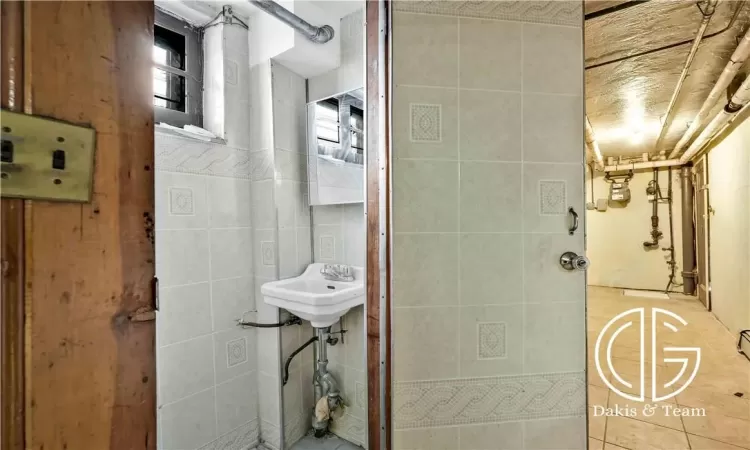 Bathroom with tile walls, tile patterned flooring, and sink