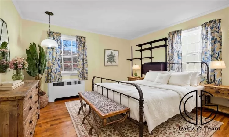 Bedroom with dark hardwood / wood-style flooring, radiator, and crown molding