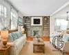 Living room featuring built in features, crown molding, a fireplace, light wood-type flooring, and an inviting chandelier