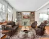 Living room with an inviting chandelier, hardwood / wood-style floors, a fireplace, crown molding, and built in features