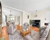 Living room with a chandelier, light wood-type flooring, and ornamental molding