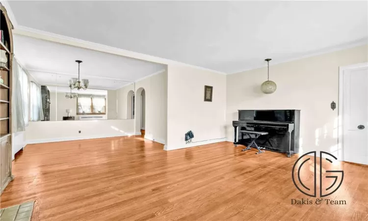 Living room featuring ornamental molding, light hardwood / wood-style floors, and an inviting chandelier