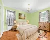 Bedroom with radiator heating unit, light hardwood / wood-style flooring, crown molding, and a notable chandelier