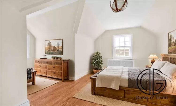 Bedroom featuring radiator heating unit, light hardwood / wood-style flooring, and lofted ceiling