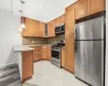 Kitchen featuring kitchen peninsula, appliances with stainless steel finishes, light stone countertops, tasteful backsplash, and decorative light fixtures