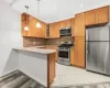 Kitchen with stainless steel appliances, kitchen peninsula, pendant lighting, light hardwood / wood-style floors, and decorative backsplash