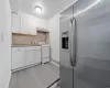 Kitchen with light hardwood / wood-style floors, stainless steel fridge, backsplash, white range with gas cooktop, and white cabinets