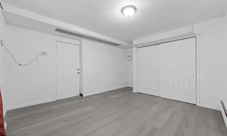 Basement with light hardwood / wood-style floors and baseboard heating