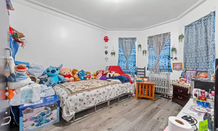 Bedroom featuring light wood-type flooring and crown molding