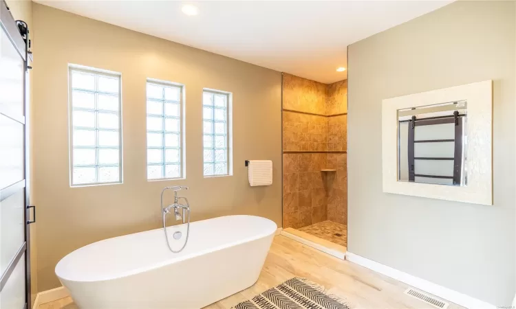 Bathroom featuring wood-type flooring and shower with separate bathtub