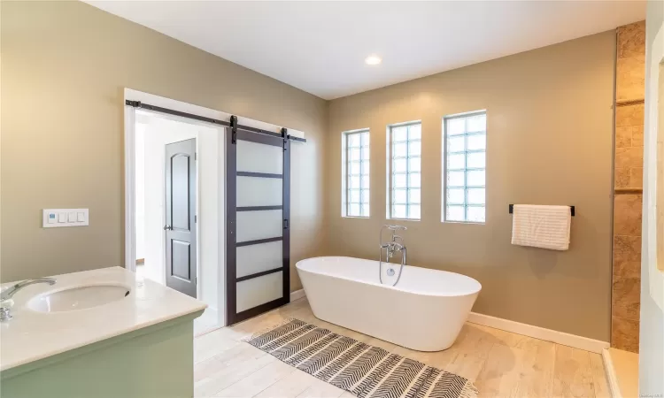 Bathroom with a bathtub, vanity, and wood-type flooring