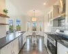 Kitchen featuring white cabinetry, sink, wall chimney exhaust hood, and appliances with stainless steel finishes