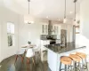 Kitchen with white cabinets, hanging light fixtures, wall chimney exhaust hood, dark hardwood / wood-style floors, and stainless steel appliances