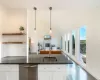 Kitchen featuring dark stone counters, sink, decorative light fixtures, dark hardwood / wood-style floors, and white cabinetry