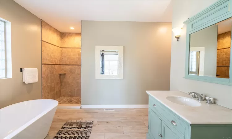 Bathroom with hardwood / wood-style floors, vanity, separate shower and tub, and a wealth of natural light