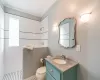 Bathroom with tiled shower, toilet, vanity, and ornamental molding