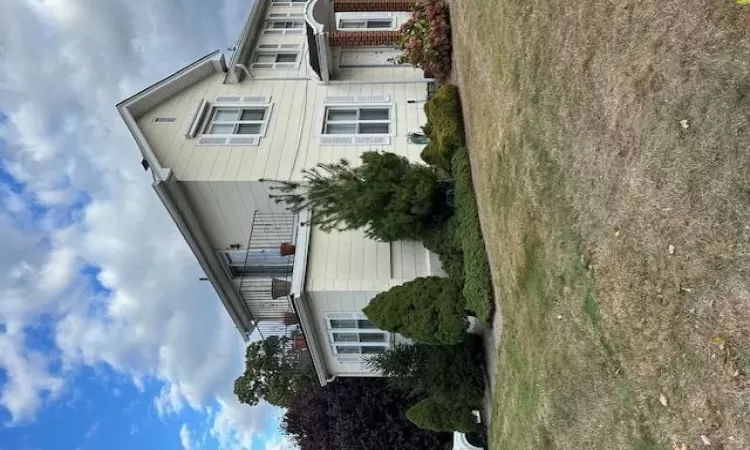 View of side of home with a lawn and a balcony