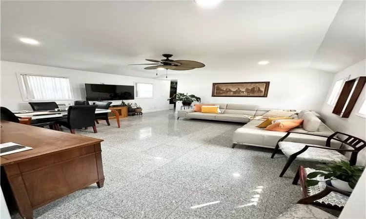 Living room with ceiling fan, plenty of natural light, and vaulted ceiling