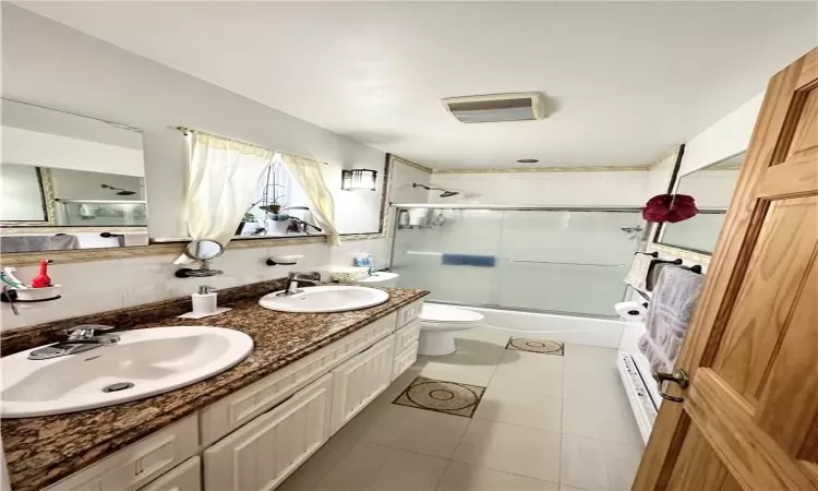 Full bathroom with enclosed tub / shower combo, tile patterned flooring, vanity, and toilet