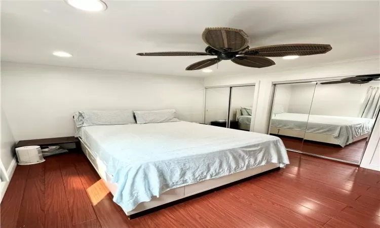 Bedroom featuring ornamental molding, two closets, ceiling fan, and dark hardwood / wood-style flooring