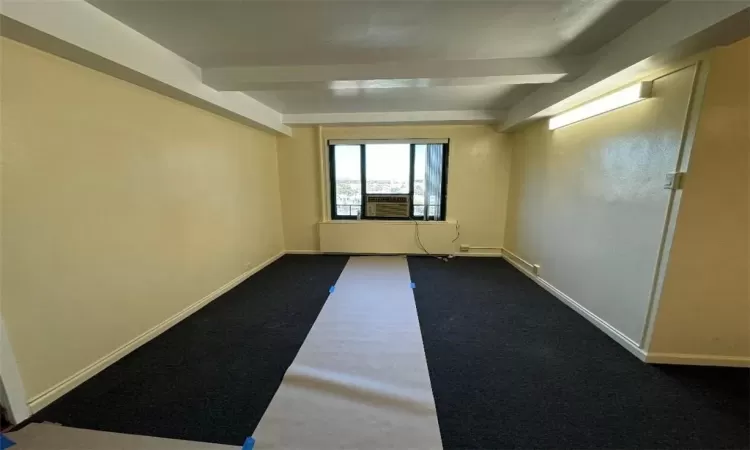 Spare room featuring beamed ceiling and carpet flooring