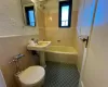 Bathroom featuring toilet, tiled shower / bath, and tile walls