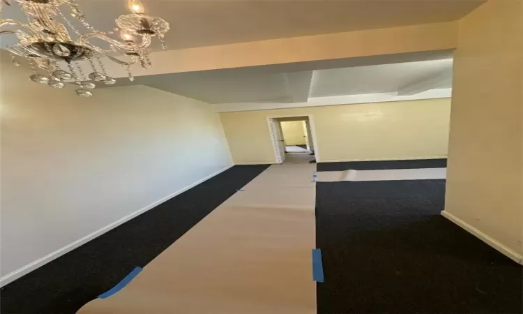 Hallway with carpet and a chandelier