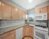 Kitchen featuring sink, white appliances, light tile patterned floors, decorative backsplash, and light brown cabinetry