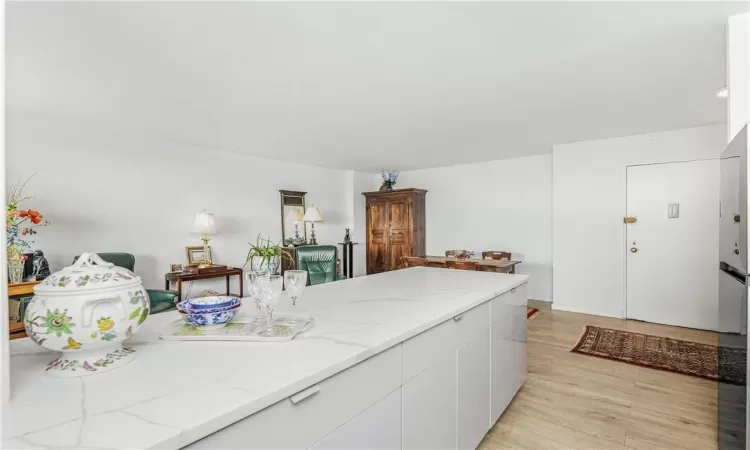 Kitchen featuring light wood-type flooring, white cabinetry, and light stone countertops