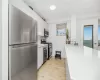 Kitchen with decorative backsplash, appliances with stainless steel finishes, white cabinetry, light hardwood / wood-style floors, and light stone counters