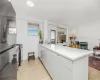 Kitchen featuring light wood-type flooring, stainless steel range with gas cooktop, kitchen peninsula, and light stone countertops