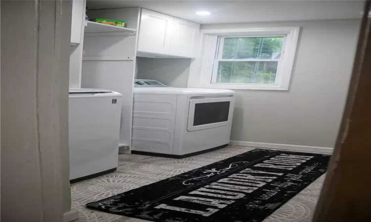 Washroom with washer and clothes dryer and cabinets