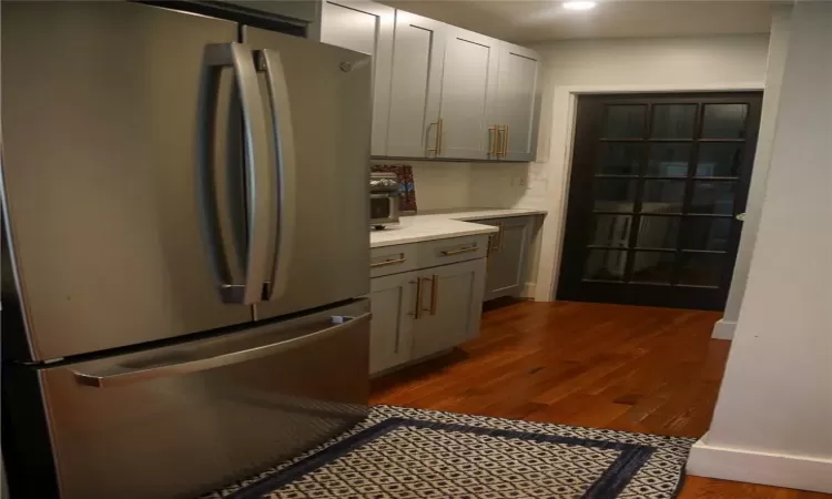 Kitchen with tasteful backsplash, dark wood-type flooring, gray cabinets, and stainless steel fridge