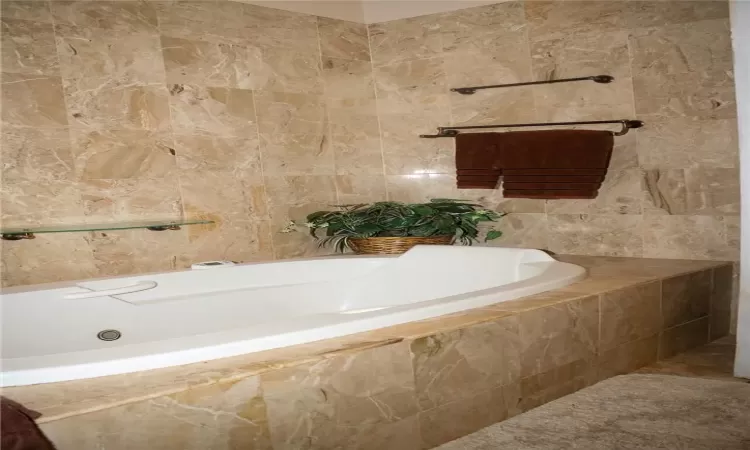 Bathroom featuring tile walls and a relaxing tiled tub