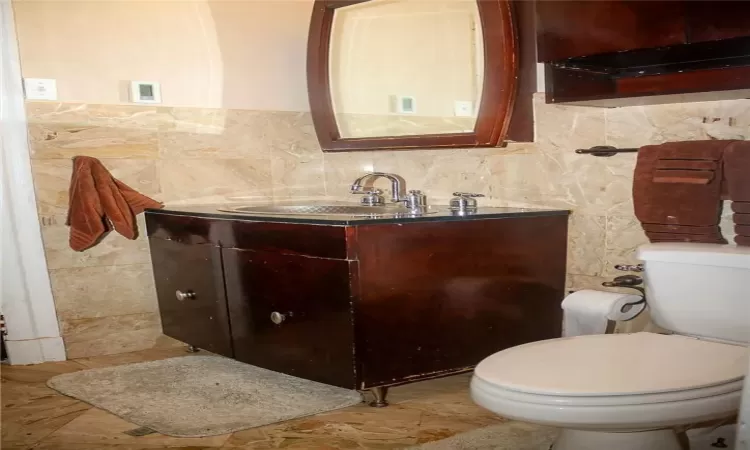 Bathroom featuring backsplash, vanity, toilet, and tile patterned flooring