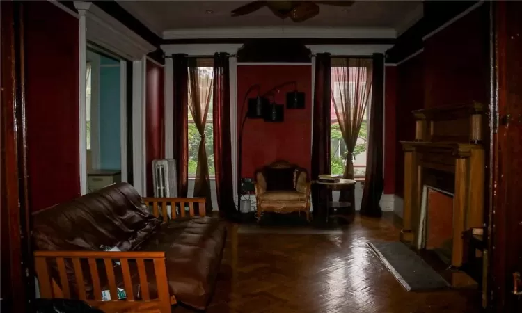 Living room featuring ceiling fan, ornamental molding, and parquet floors